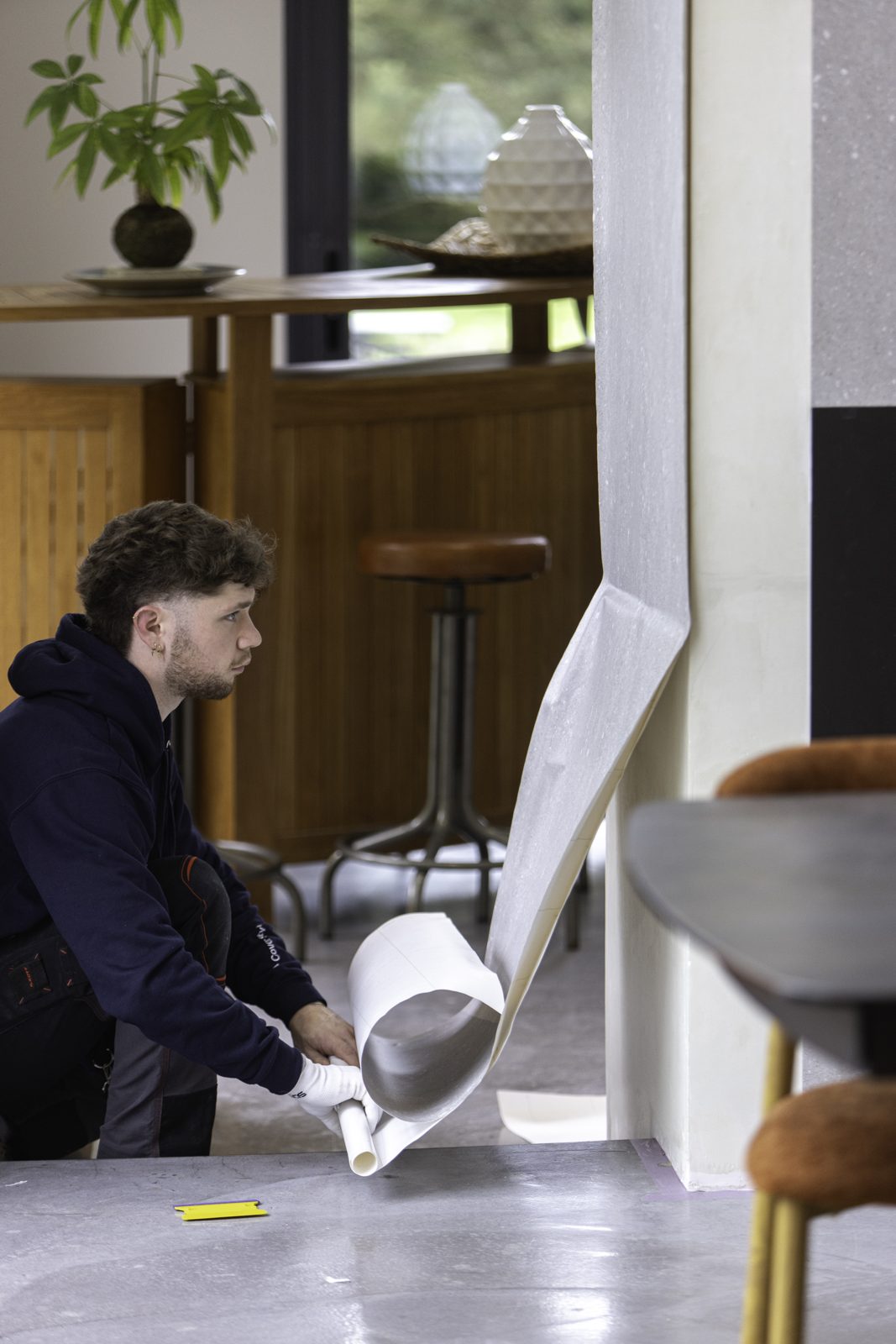 Instalador retirando el papel de protección mientras la lámina sube por la columna